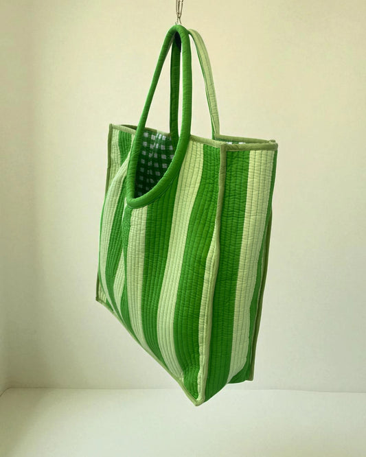 Green and white striped tote bag hanging against a plain background