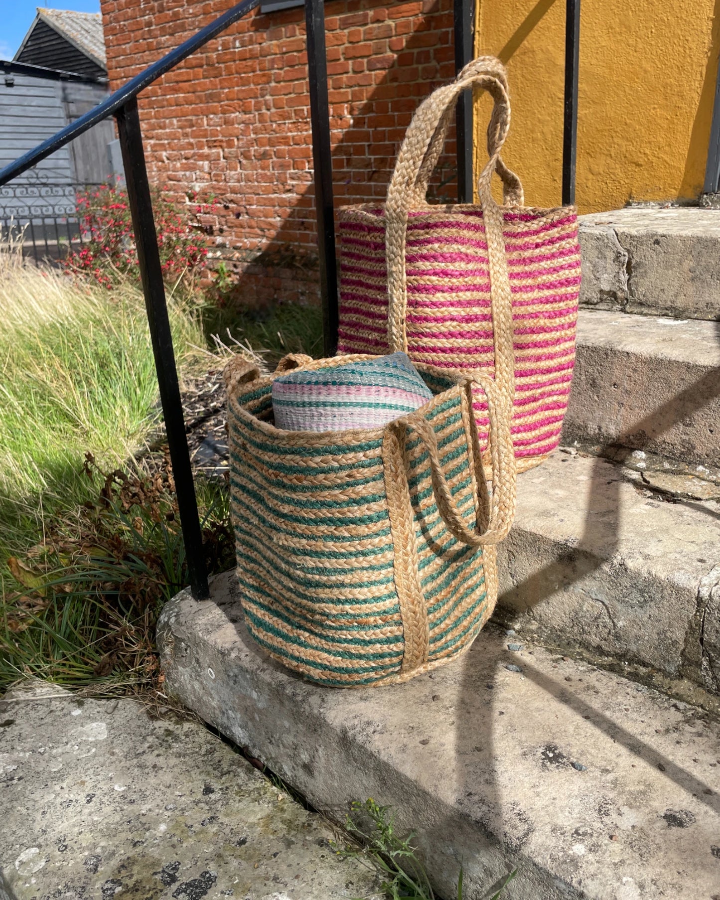 pair of two woven bags in pink and green with shoulder straps