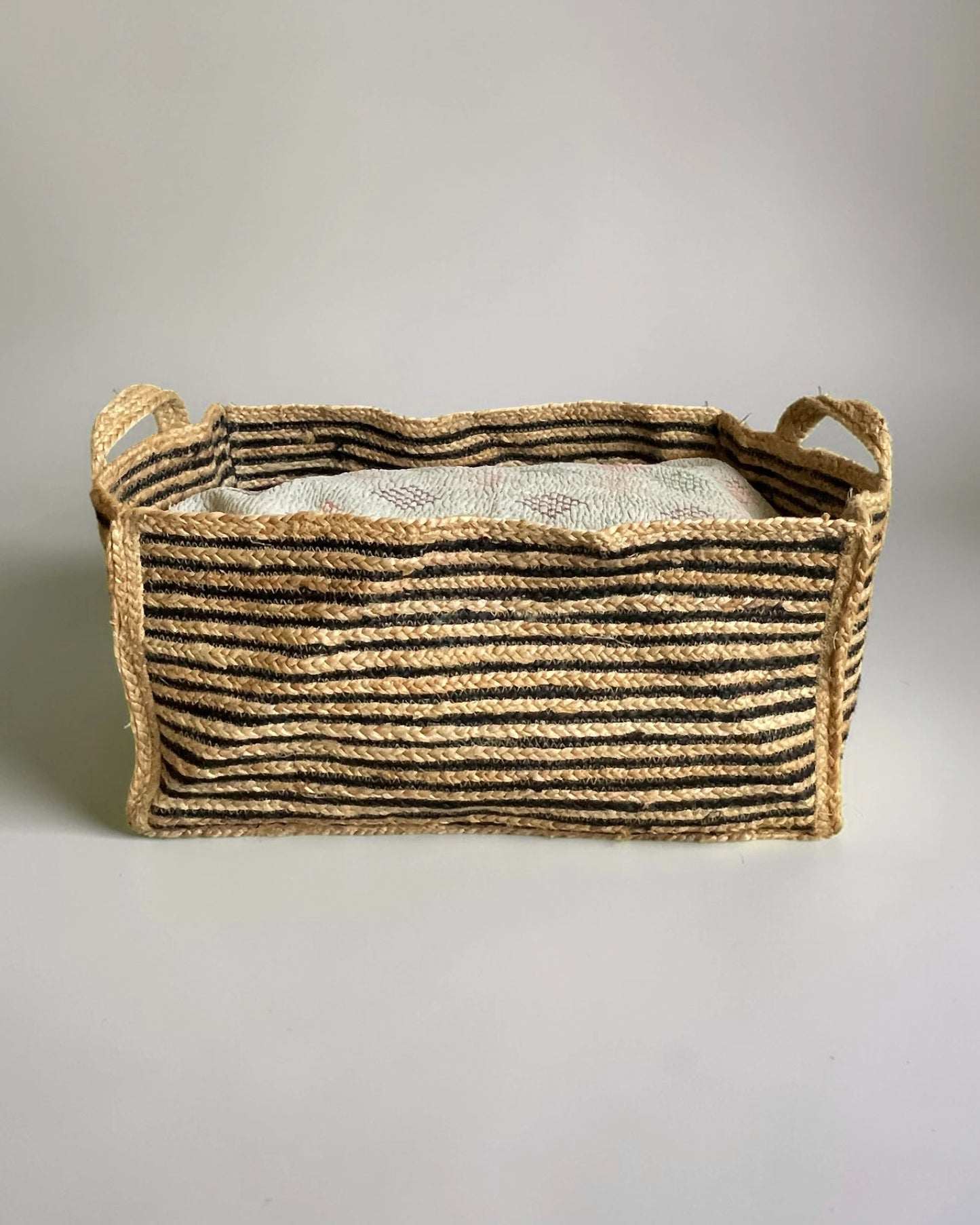 Foldable black and natural jute basket flattened when empty