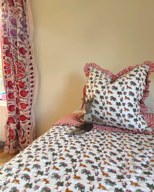 Close up of hand block printed jungle animal cotton fabric on Ranthambore kids quilt bedding set showing artisan detail, ruffle edging and kids bedroom styling ideas