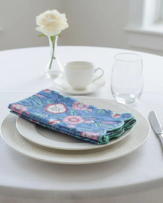 Handmade cotton table napkins featuring a pink floral pattern on sky blue fabric with decorative scalloped edging
