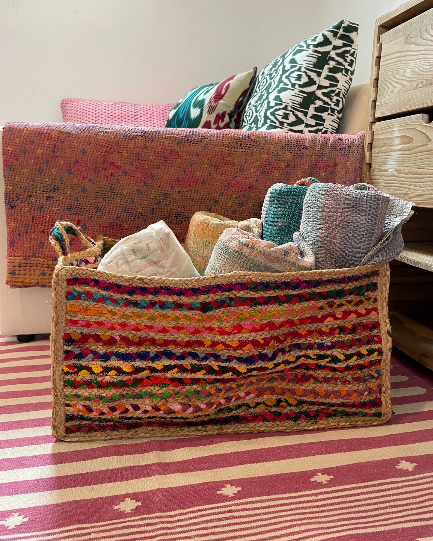 Side view of extra large storage basket in bright colourful rainbow threads with natural jute