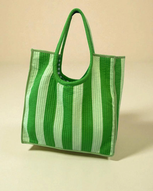 Green striped cotton beach or day bag on a beige background