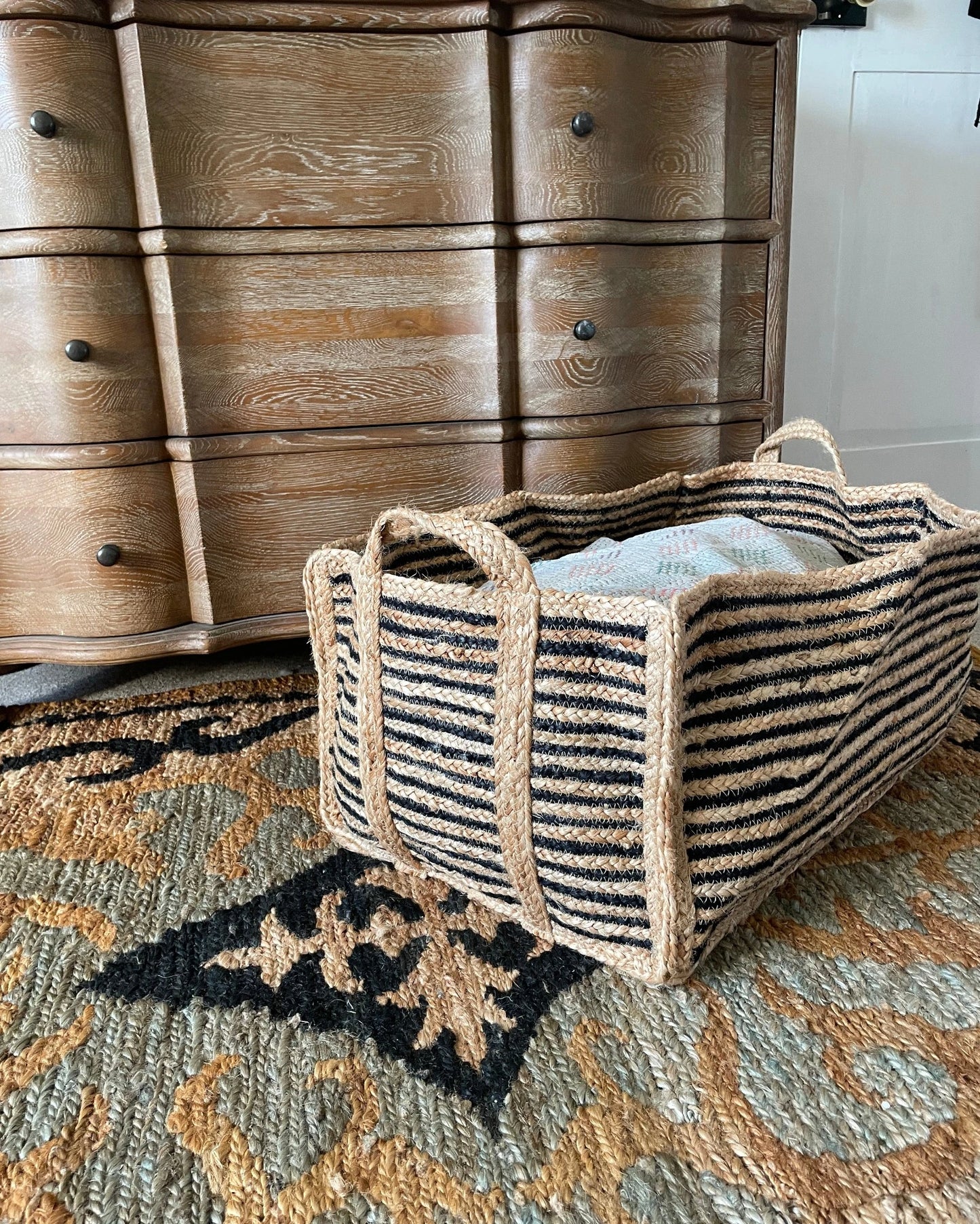Front view of handwoven black and natural jute basket for home storage