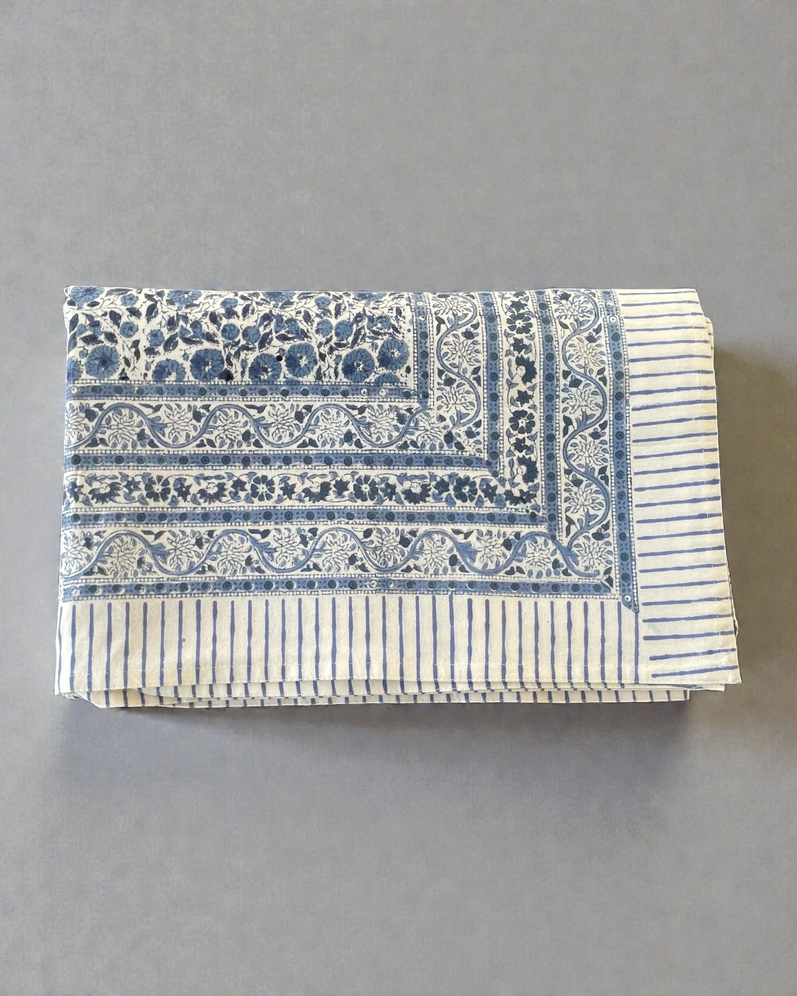 artisan blue and white tablecloth with floral border and striped hem detail