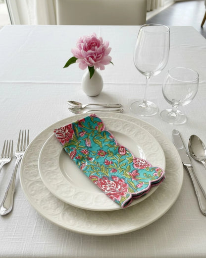 Handcrafted block print cotton napkin with blue floral pattern and pink scalloped trim