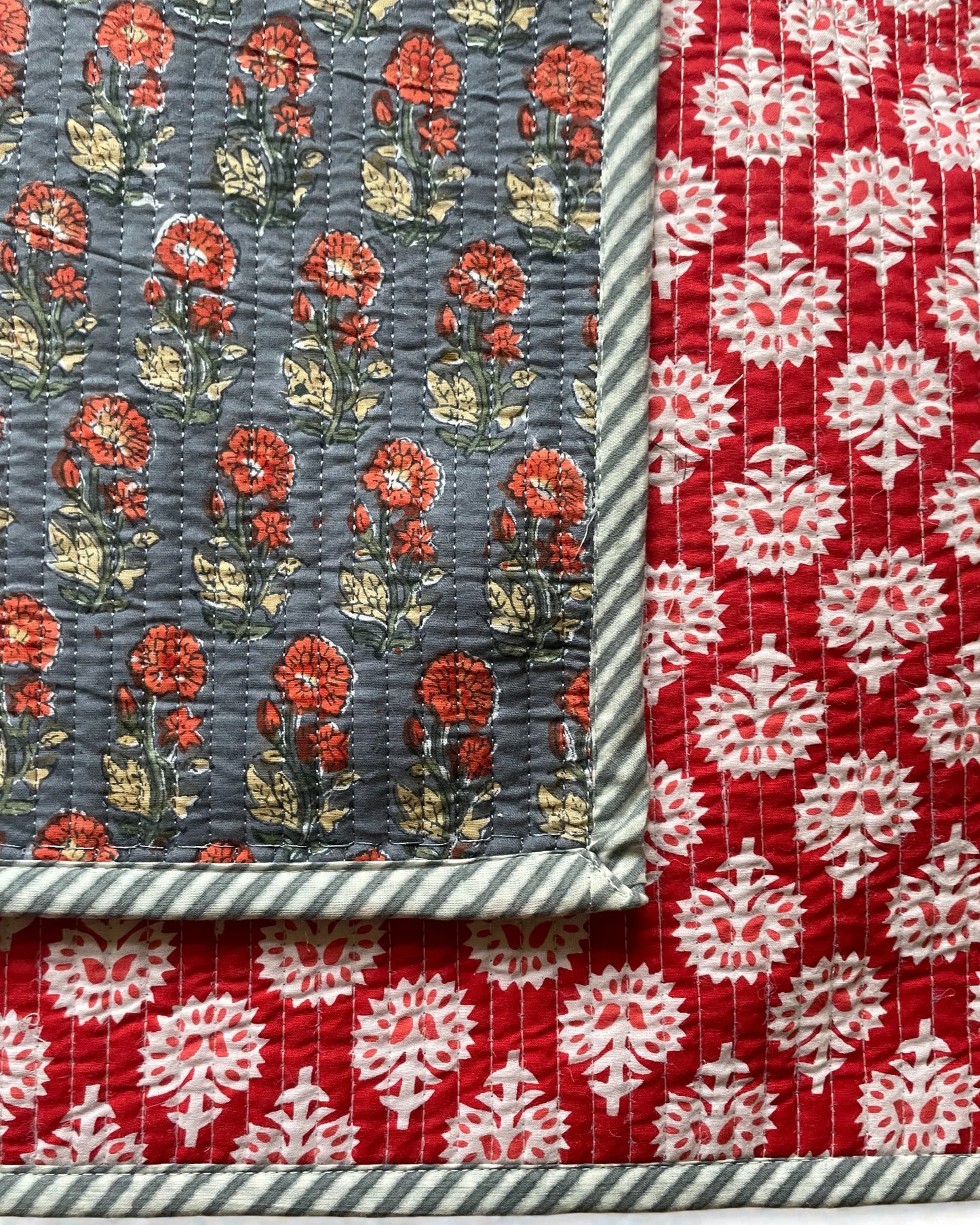 Reversible quilted placemats in scarlet and grey tones on a dining table