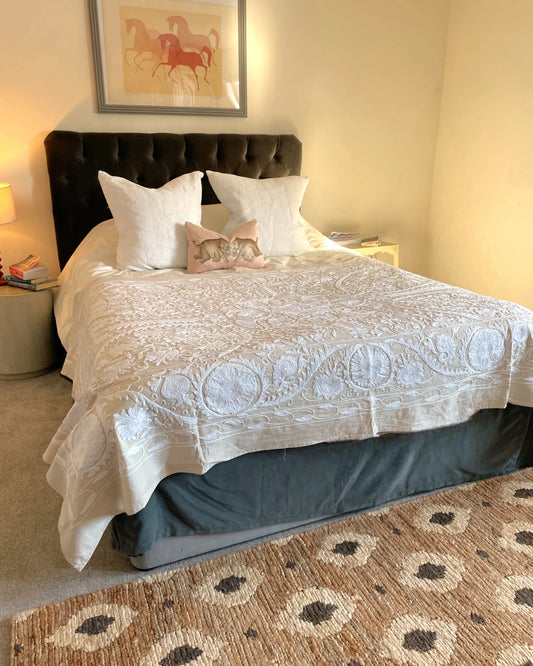 Hand stitched ecru and white suzani quilt styled as a king size bedspread with white embroidery on an off white linen base