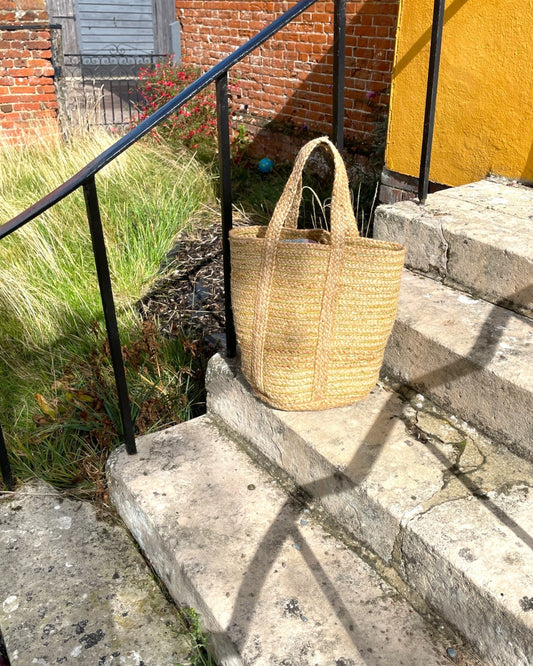 Woven basket bag in natural jute and bright gold on stone steps 