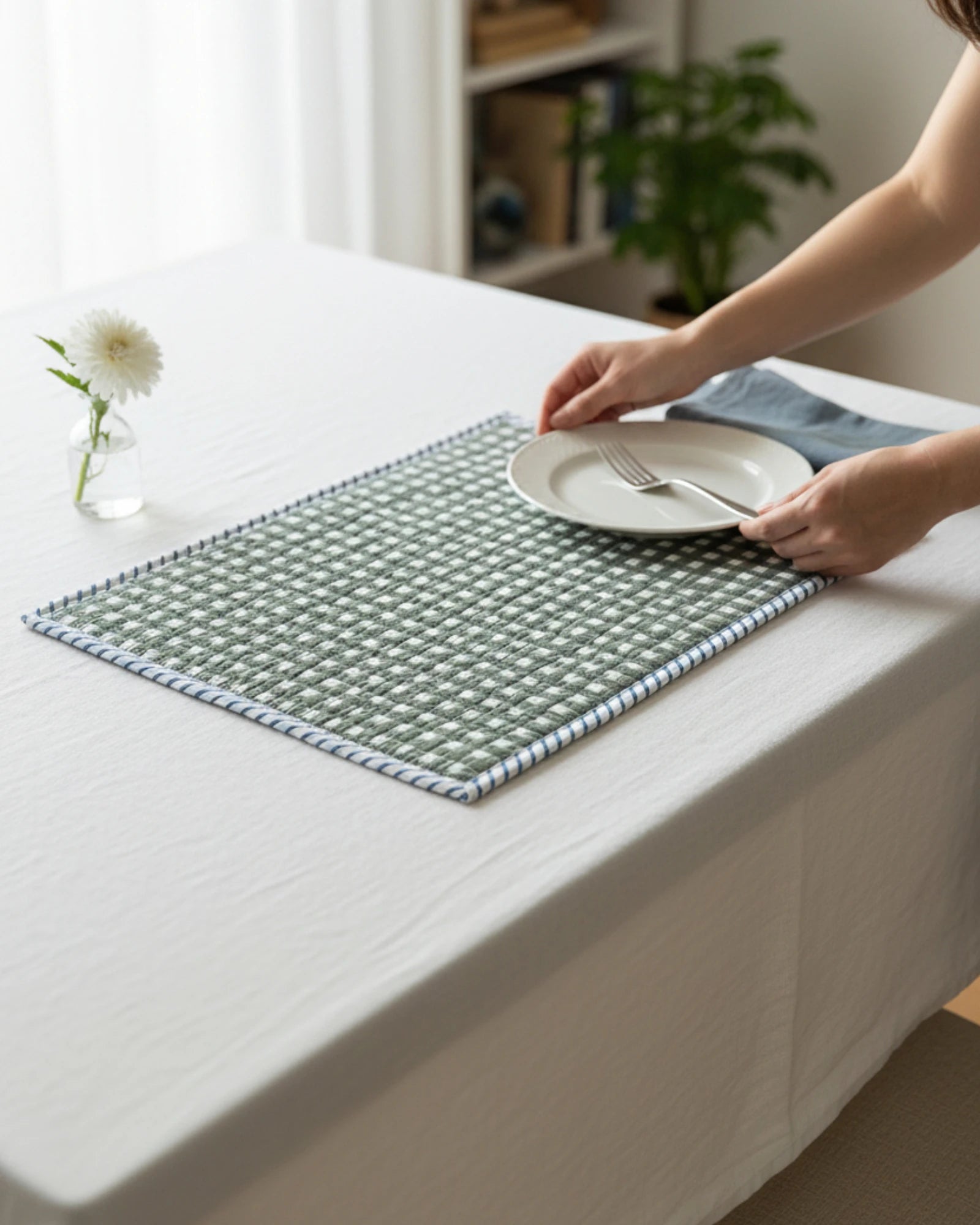 Detail of quilted cotton placemat showing blue striped border with green gingham base on an elegant table setting