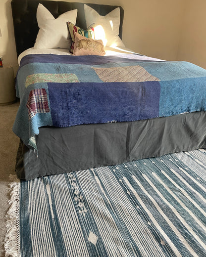 eclectic bedroom with blue rug and decorative bed