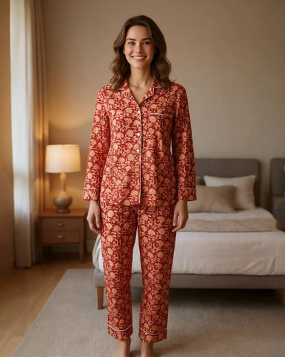 Woman wearing a red floral pajama set in a bedroom.