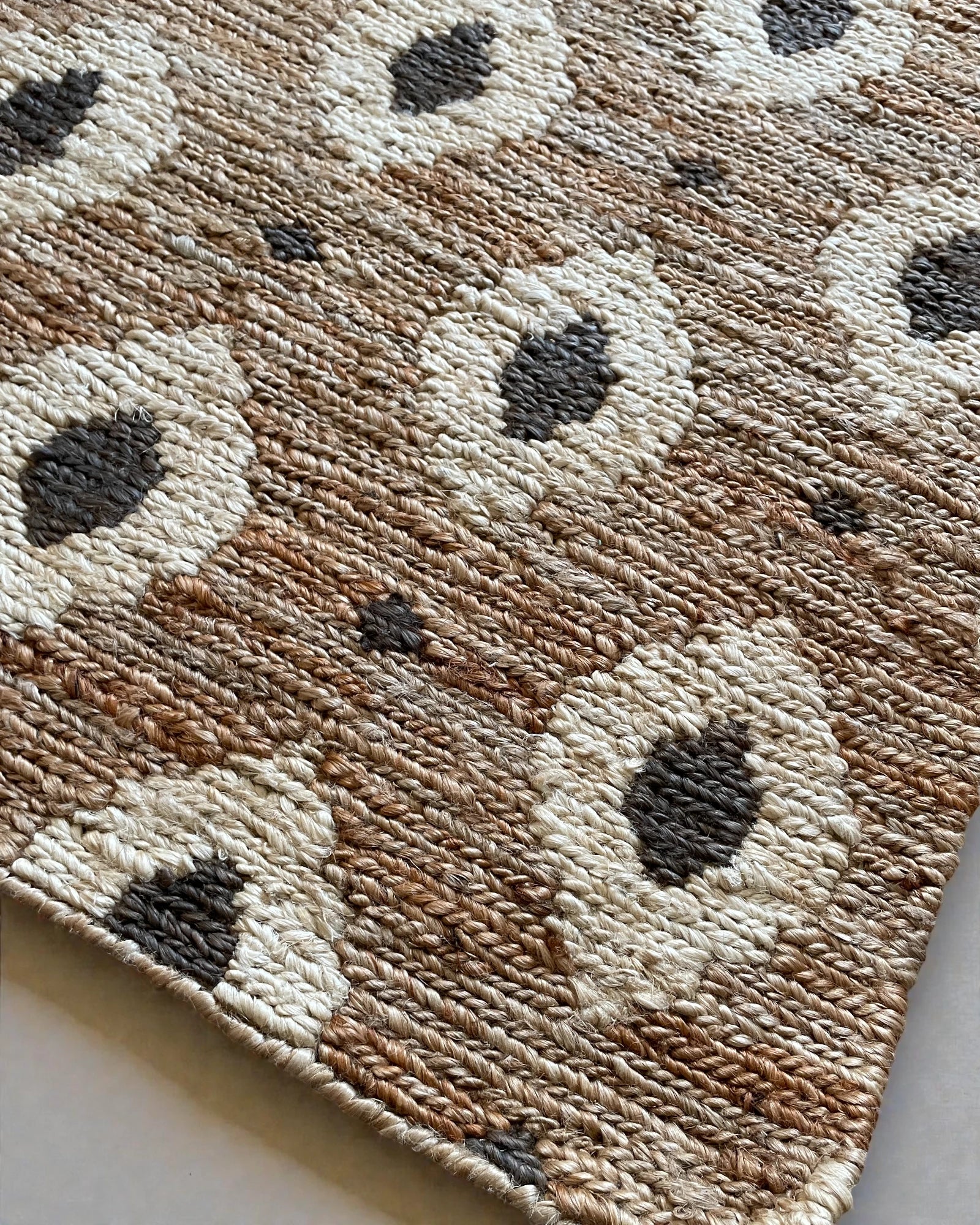 Close up of flat woven jute runner showing plaited Oushak weave and subtle animal print pattern