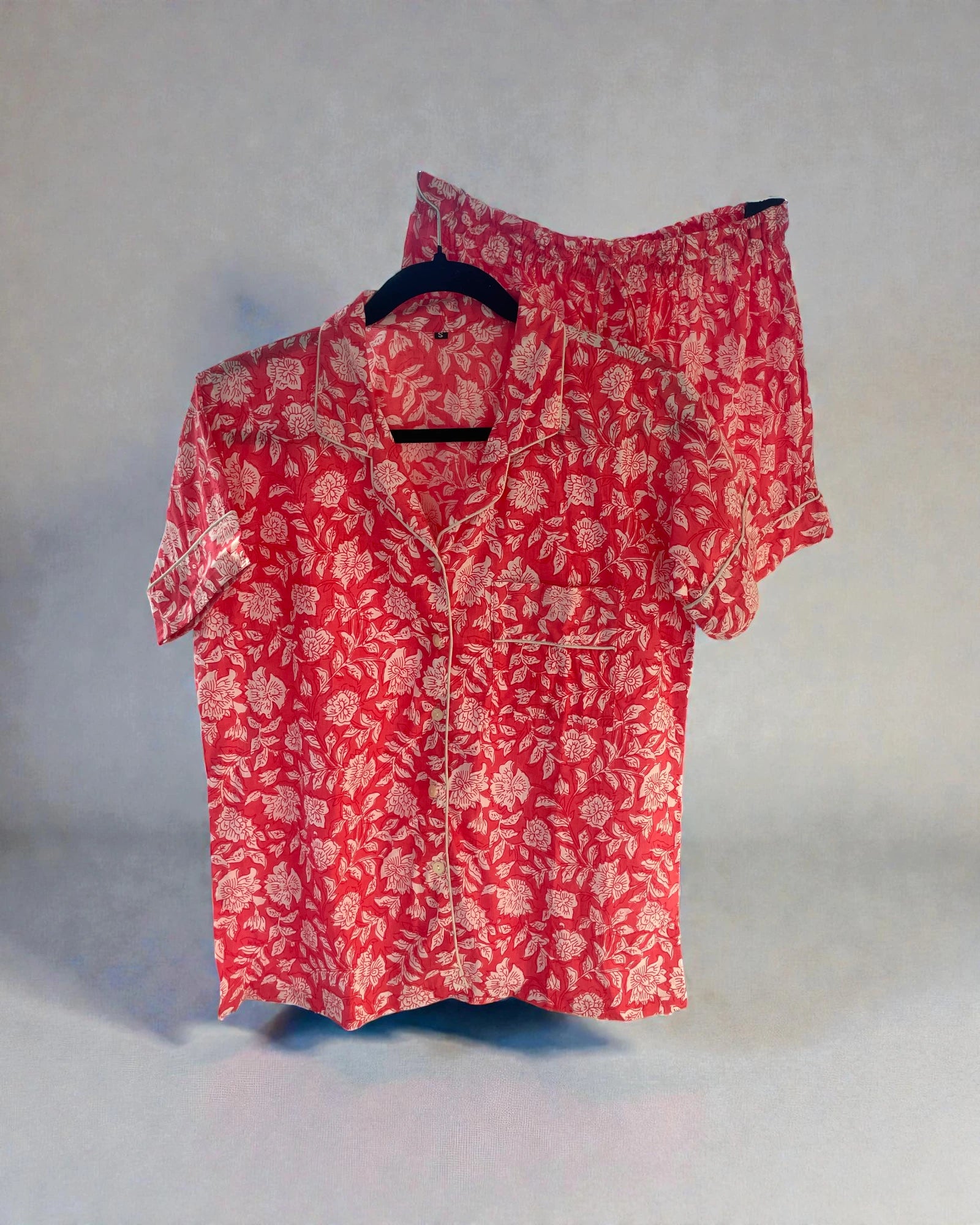 pink floral cotton pyjama set with short sleeve shirt and shorts hanging on hanger