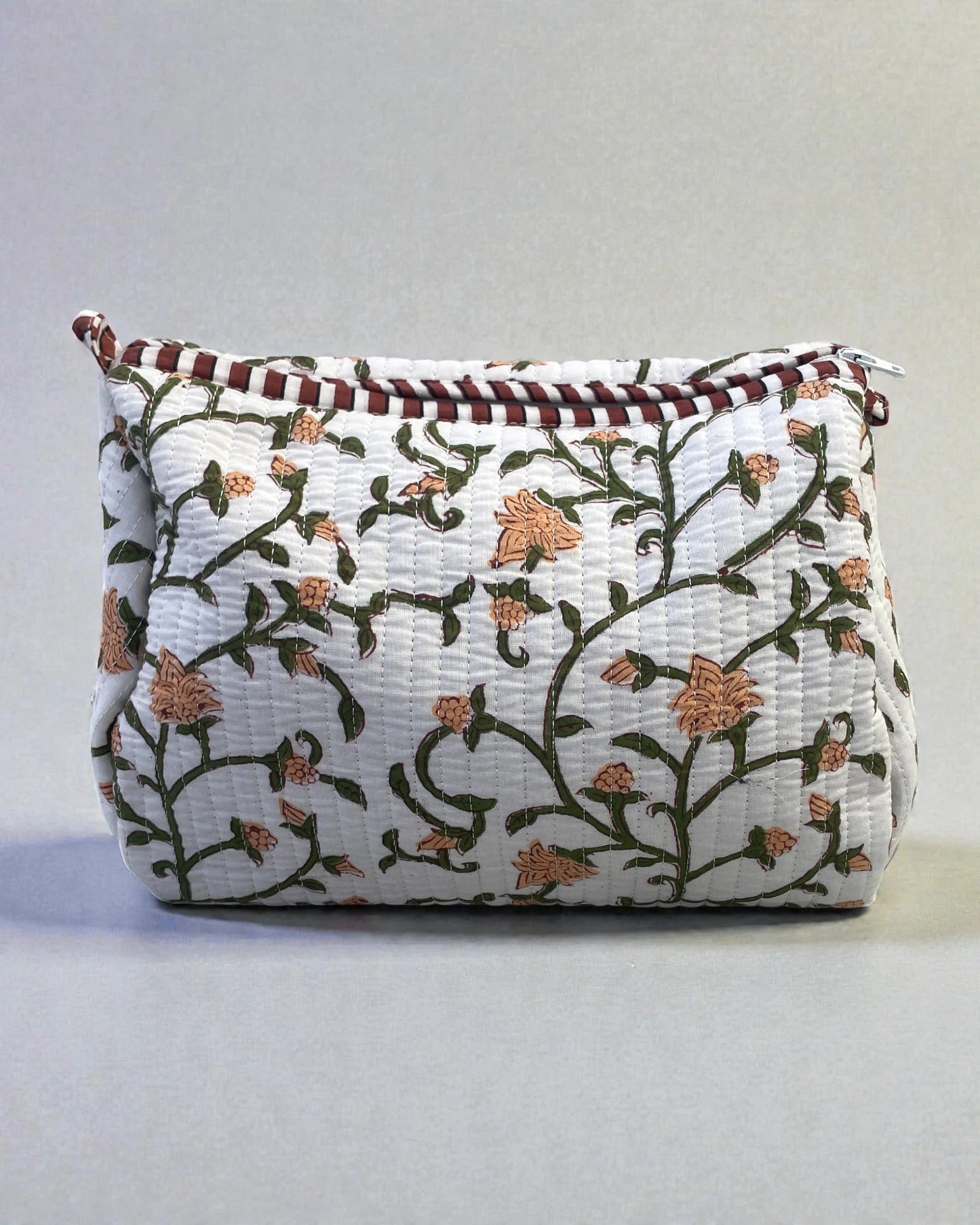 Quilted cotton toiletry bags with green floral print styled as a coordinated set, ideal for travel or bathroom storage.