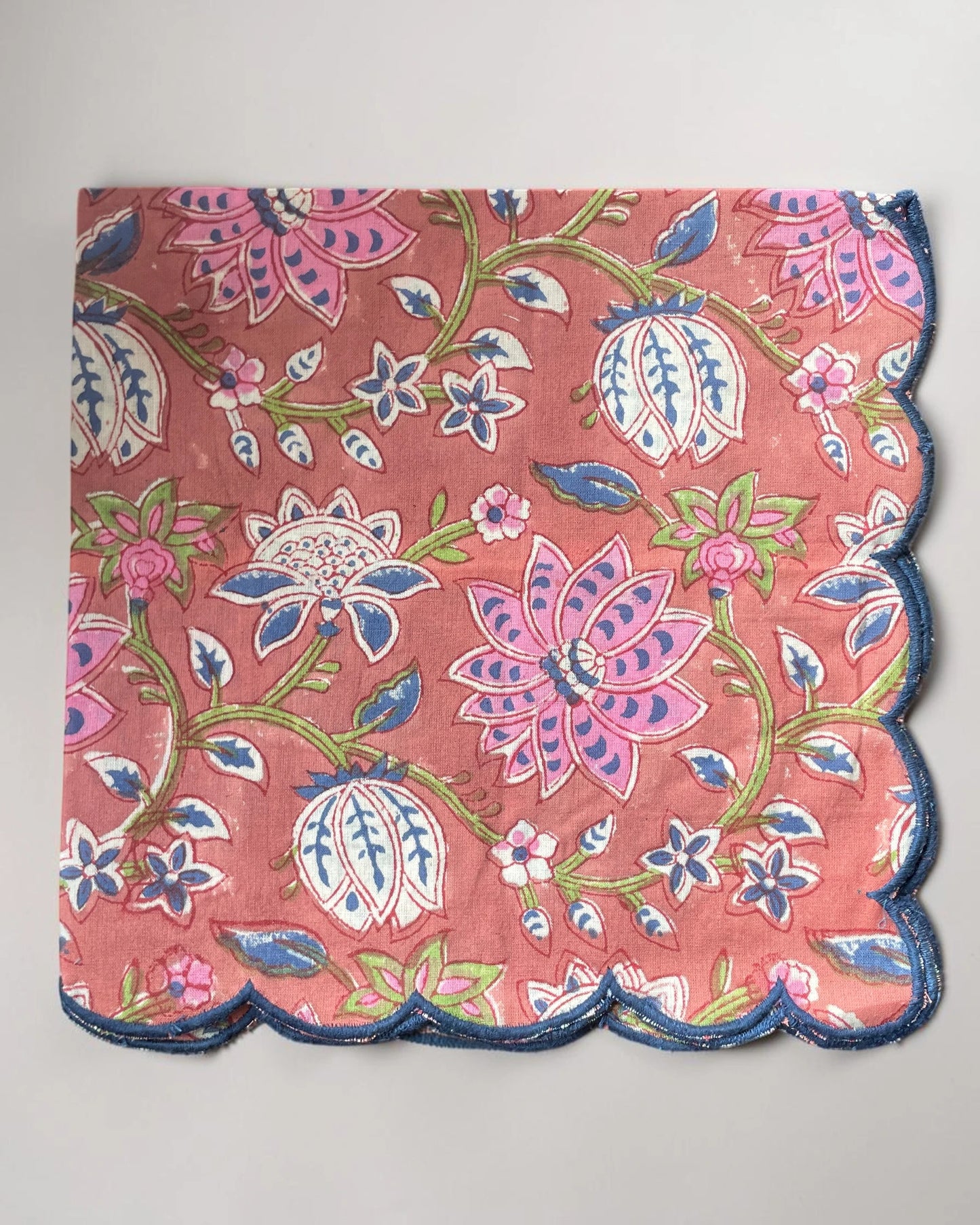 Set of six scalloped cotton napkins in a muted red print with contrasting navy blue edging