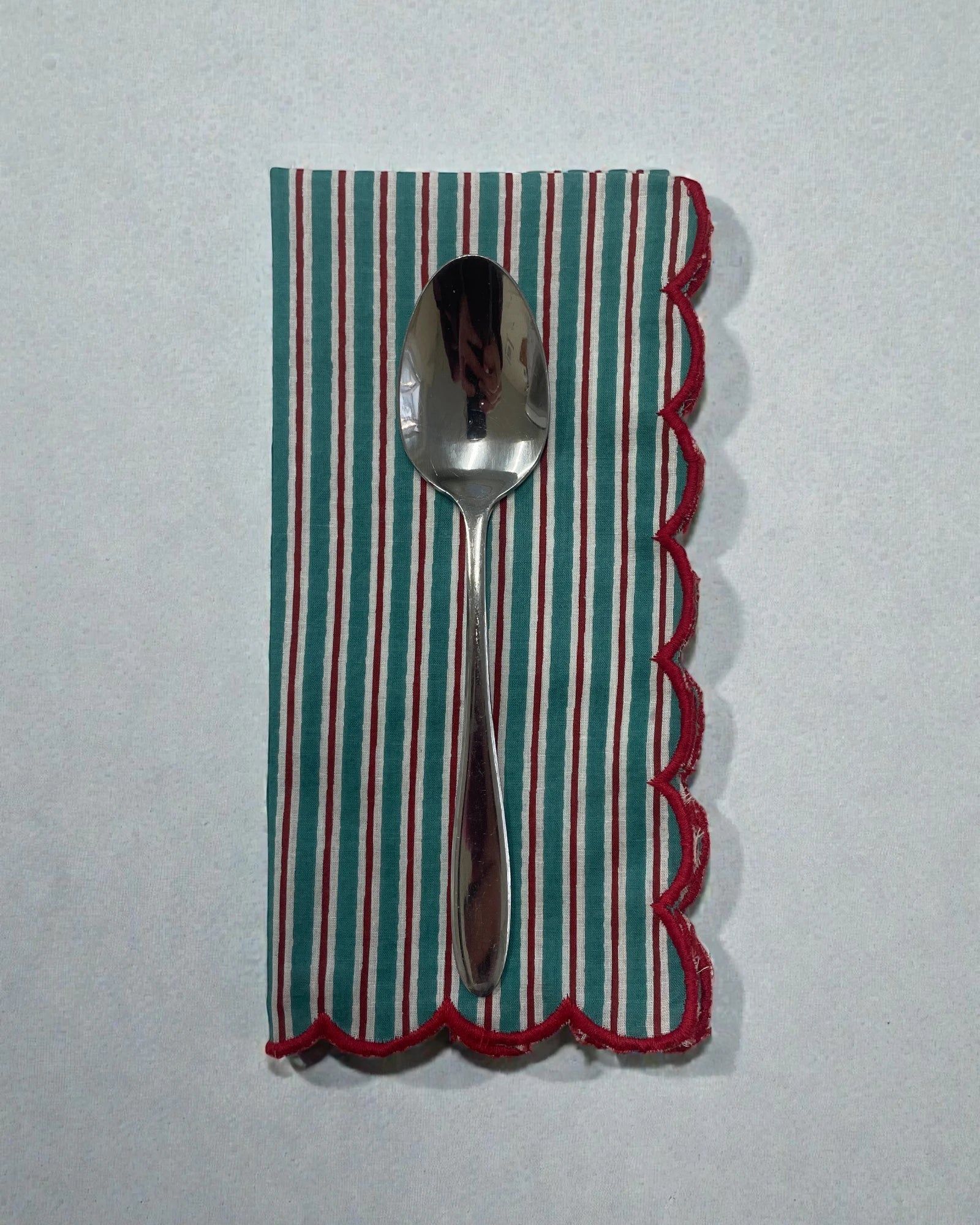 Reusable striped napkin with red scalloped edging for table setting