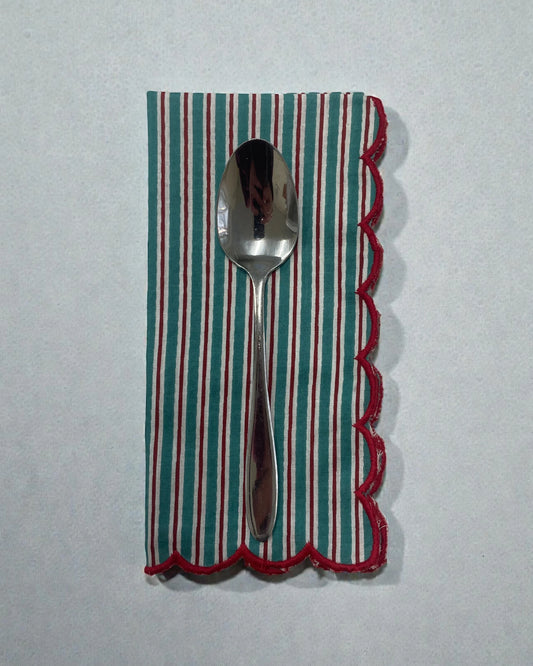 Reusable striped napkin with red scalloped edging for table setting