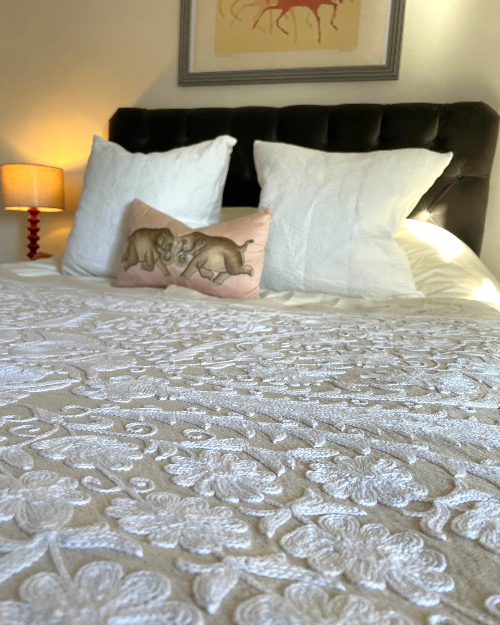 White hand stitched suzani embroidery detail on off white linen quilt