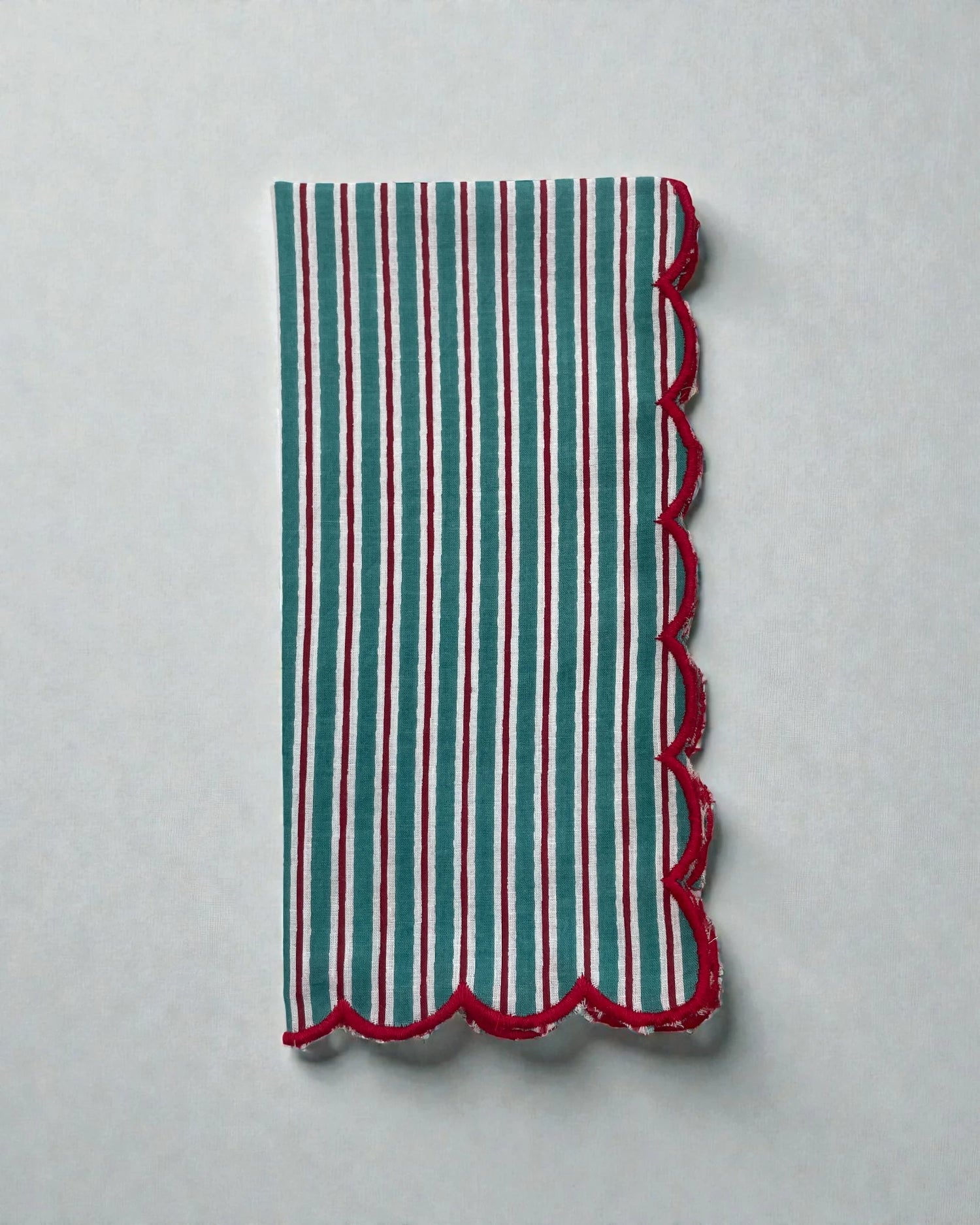 Teal and white striped cotton napkin with red scalloped edge